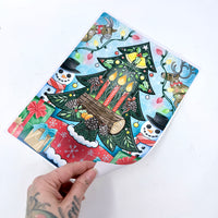 Colorful Christmas-themed notebook with a hand holding it on a white background